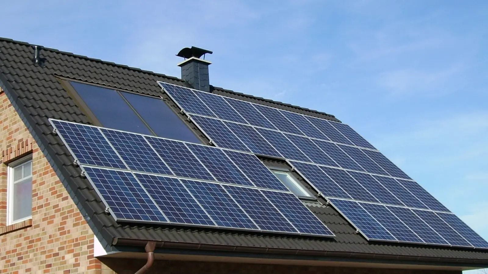 A suburban house with a rooftop solar array on the main roof plane