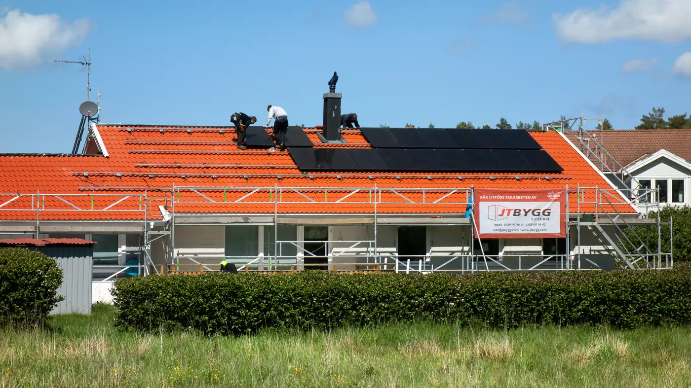 A crew installing solar panels on a house roof